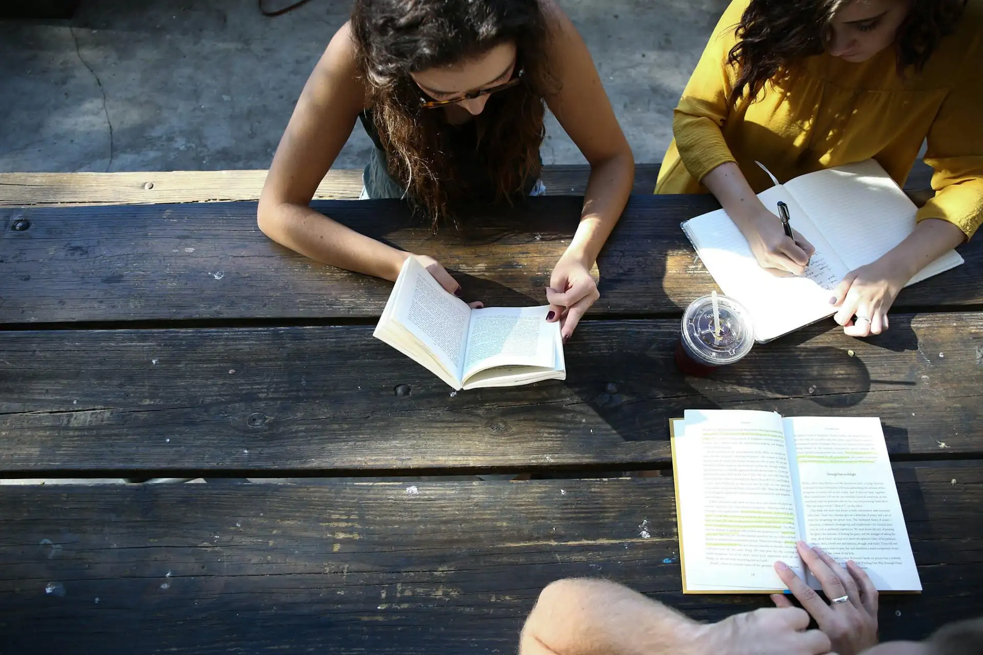 Two students reading and taking notes at a wooden table